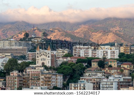 sunrise at messina harbor with view on the city center and mountains in the background, italy