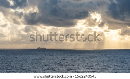 sunset on the sea with beautiful cloud patterns, sun rays, ship