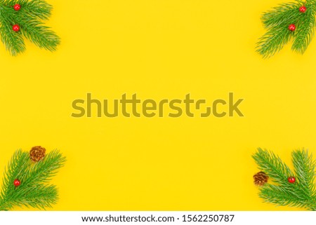 Christmas border with branches of spruce, mountain ash, cones on a yellow background. The concept of winter holidays: New Year, Christmas. Layout with copy space for your text.