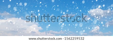A long shot of blue sky And white clouds With snow falling.