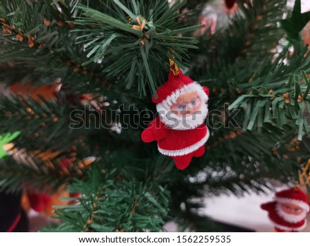 A close up of the santa doll in red dress On a green christmas tree