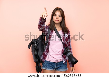 Young photographer girl over isolated pink background touching on transparent screen