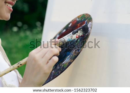 young woman with a brush in her hand and with paints for painting