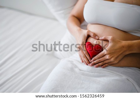 Pregnant woman is happy to take care of the child at birth.Happy pregnant woman is touching her belly.Pregnant woman show love by making a heart shape on their belly.
