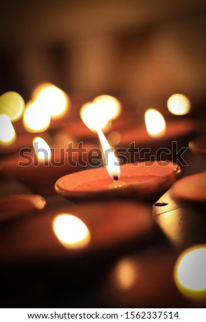 beautiful picture of burning Diwali or Deepawali Diyas showing many Diya with focus on central Diya. Perfect image to show Indian traditions, culture, festivals and celebration