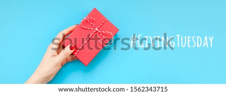 Giving Tuesday is a global day of charitable giving after Black Friday shopping day. Charity, give help, donations and support concept with text message sign and woman hand holding red gift box Royalty-Free Stock Photo #1562343715