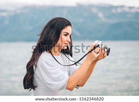 Young beautiful woman taking pictures outside with vintage film camera