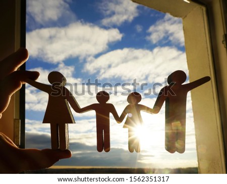 male hand holding family wooden figure on blue clousy sky background. open window. window frame. sunny summer day. family together holding hands. 