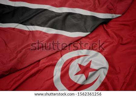 waving colorful flag of tunisia and national flag of trinidad and tobago. macro