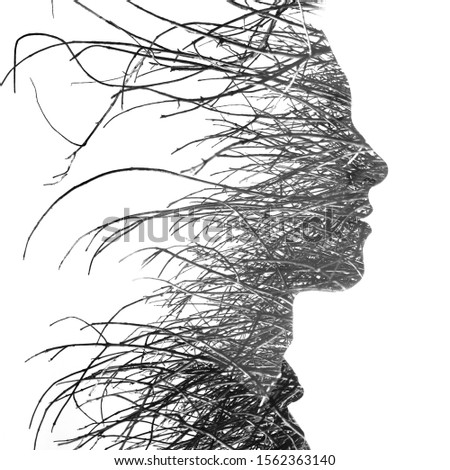Double exposure close up profile portrait of an attractive man with strong features combined with thin tree branches, black and white