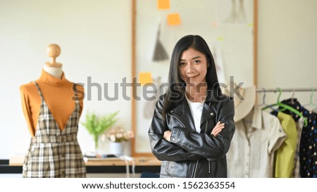 Fashion designer standing near mannequin in studio.