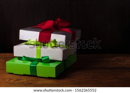 Colorful gift boxes with ribbon bows on a brown wooden background with copy space. Holidays concept, Christmas, New Year, three presents mockup. Minimal style, trendy packaging in vintage tone.
