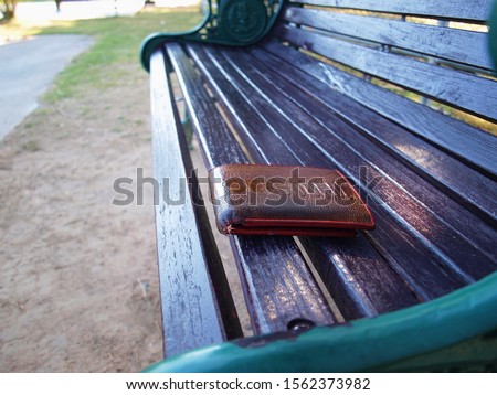 Brown wallet on a park bench Loss of property due to forgetting On the background of a black wooden bench With copy space.