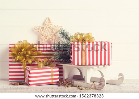 Gift boxes with ornaments and sleigh on white wooden background