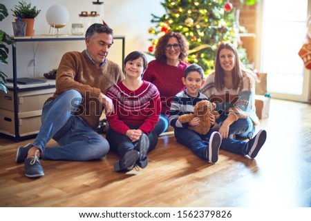 Beautiful family smiling happy and confident. Sitting on the floor and posing around christmas tree at home