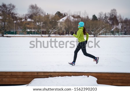 Photo of young athlete woman running in winter park
