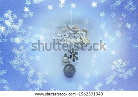 A beautiful hand made cloud made from metal paper, snowflakes and christmas balls surrounded by stars (double exposire effect)