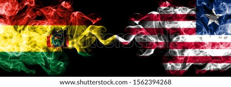 Bolivia, Bolivian vs Liberia, Liberian smoky mystic states flags placed side by side. Concept and idea thick colored silky abstract smoke flags