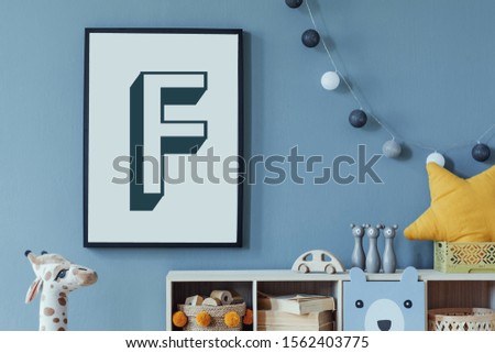 Stylish scandinavian newborn baby room with wooden cabinet, toys, mock up poster frame and children's accessories. Modern interior with eucalyptus background wall and cottona balls. Modern home decor.