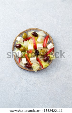 Salad with Green and Kalamata Olives, Red Pepper and Feta Cheese on Bright Stone Background. Healthy Snack Idea. Top view. Copy space. 