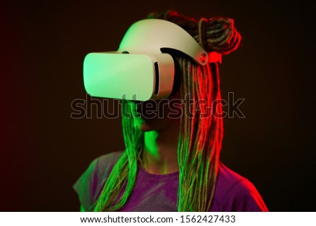 Woman is using virtual reality headset. Neon light studio portrait.
