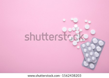 White pills on pink background with copy space, top view