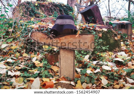 Old wooden sign with a hat in the garden covered with golden autumnal leaves