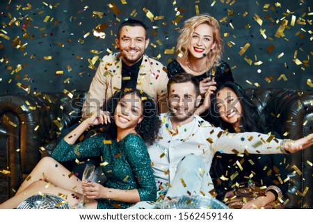 Diverse group of happy smiling friends having fun and enjoy party under confetti rain. New year, Birthday, celebration concept                 