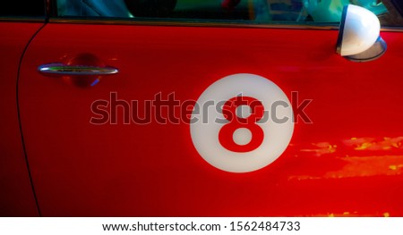 Number eight in a white circle on the door of a red car