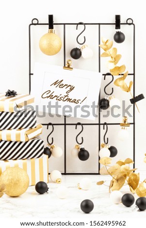 Trendy fashionable christmas decoration with gifts, greeting card and mesh board in golden,  black and white colors