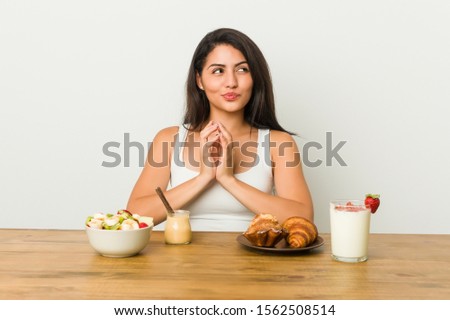 Young curvy woman taking a breakfast making up plan in mind, setting up an idea. Royalty-Free Stock Photo #1562508514