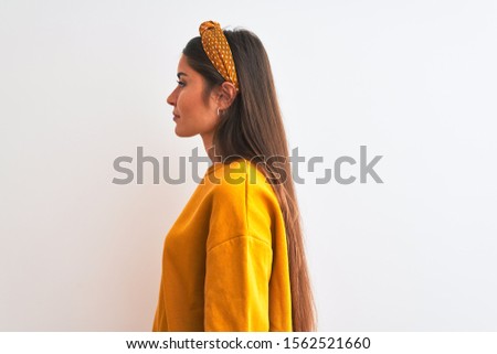 Young beautiful woman wearing yellow sweater and diadem over isolated white background looking to side, relax profile pose with natural face with confident smile.