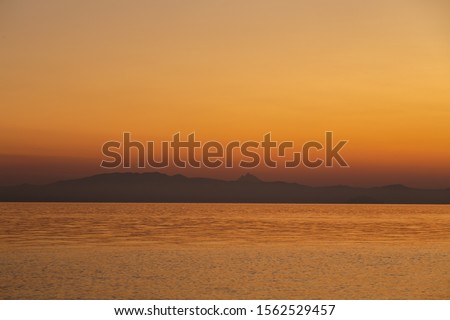 Amazing beautiful golden landscape. Sea water and golden sky before sunrise or sunset. Horizontal color photography.