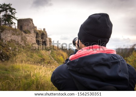 Young man tourist taking photos of castle ruin. Tourism.