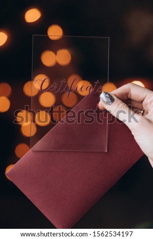 female hand with manicure holds a plastic card for text, background with bokeh. selective focus, film and grain photo