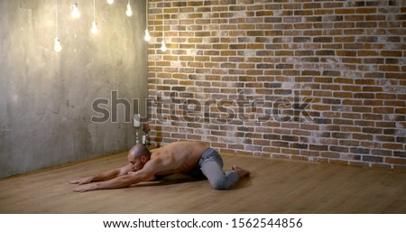 bald muscular man practicing yoga indoors. pull body sports load