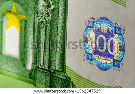 Multicolored holographic sign on a banknote of 100 euros close-up macro.