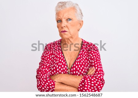 Senior grey-haired woman wearing red casual jacket standing over isolated white background skeptic and nervous, disapproving expression on face with crossed arms. Negative person.