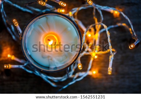 Christmas lights and candle on wooden rustic background.