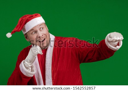 Emotional male actor in a costume of Santa Claus box and fights on a green chrome background