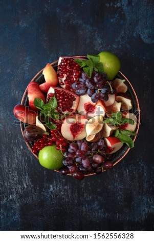 Assorted berries and fruits in a large antique dish. View from above. Copy space. Macro photo. Dark blue background.