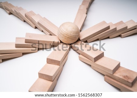 Close-up Of A Silver Ball In The Center Of Collapsed Wooden Dominoes Over White Backdrop