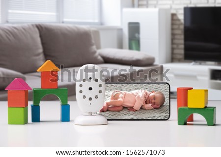 Colorful Toy Houses Arranged Near Cell Phone With Baby Image And Wireless Camera