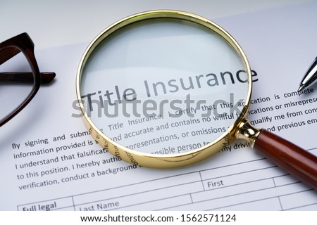 Magnifying Glass Over Title Insurance Form On Table Royalty-Free Stock Photo #1562571124