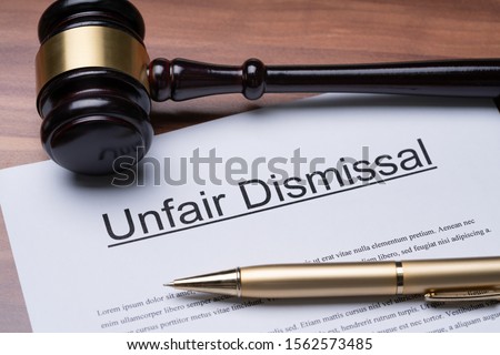 Documents Of Unfair Dismissal With Gavel And Pen On Wooden Desk In A Courtroom Royalty-Free Stock Photo #1562573485