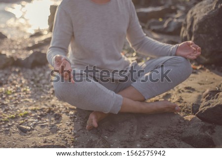 young man in meditation near the sea. Concept of pray. Adult practice yoga on the beach at sunset.