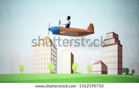 Man in aviator helmet sitting in propeller plane and flying above town. Pilot driving aeroplane on background of cartoon city. Cityscape with green grass and cute houses. Dreaming and imagination.
