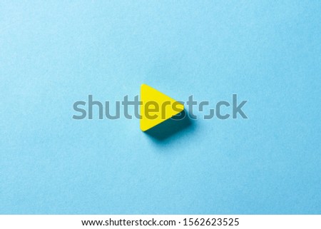 Yellow triangle on a blue background. Play sign. Minimalism. Flat lay, top view