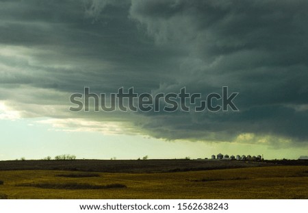 Metal grain silos silhouetted against a stormy sky.
