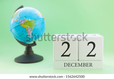 December 22. December month. White cube with numbers and globe on a blurred green background. The concept of New Year and Christmas holidays.